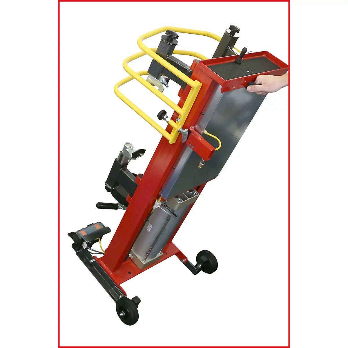 Rote, rollbare Hebevorrichtung mit gelben Schutzbügeln, Metallgehäuse. Eine Hand hält das obere Fach.